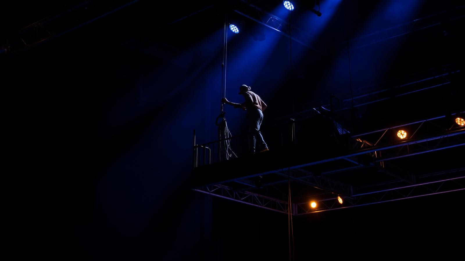 Theater rigger working from a catwalk above the stage