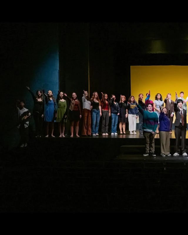 Company curtain call against a yellow lit backdrop