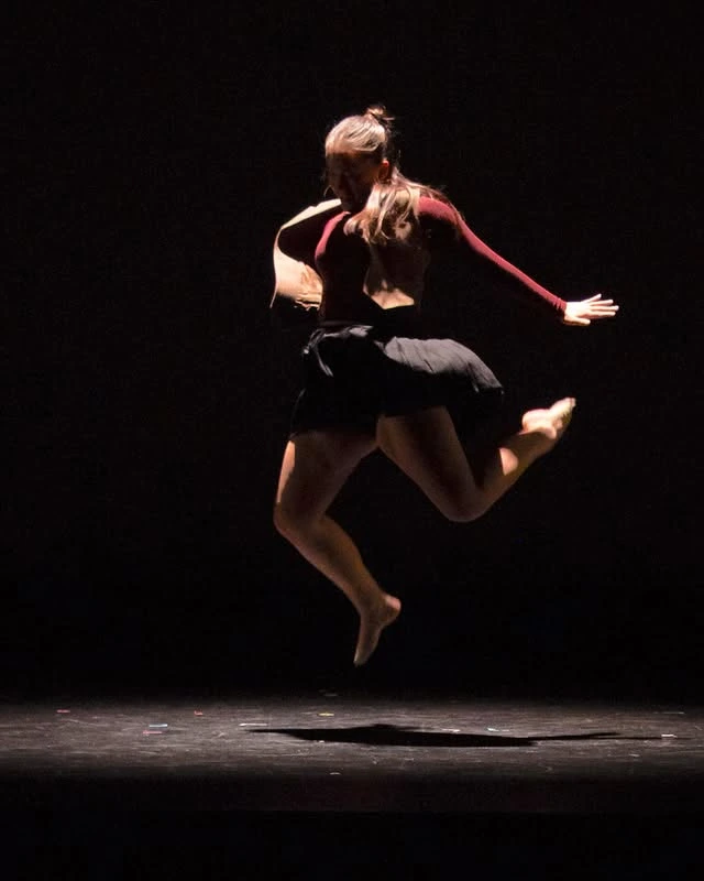 Dancer mid-leap isolated in a tight spotlight
